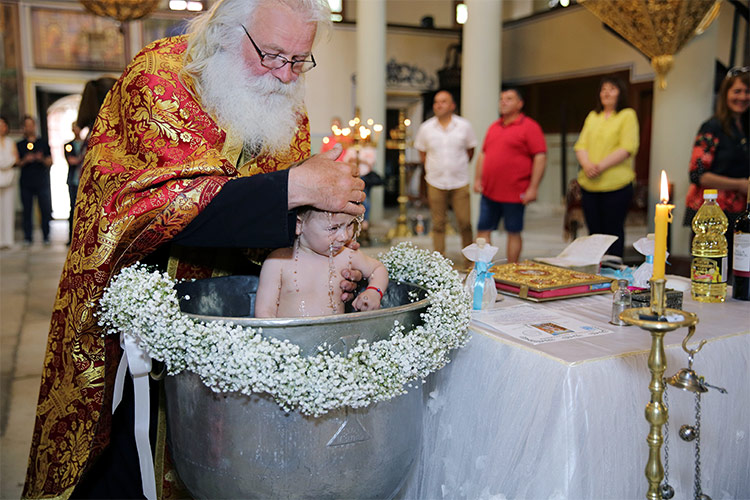 Отецът кръщава момченце в купела по време на ритуал в храм "Св. Неделя", Пловдив.