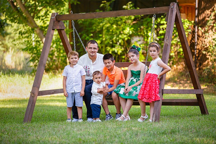 Момченце със своят баща и деца гости празнуват кръщението му в двора на Very Berry Wedding Tent, град Пловдив.