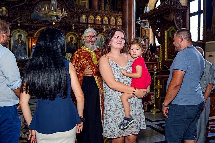 Кръстницата на момиченцето се съчетава с Христа по време на ритуал Свето Кръщение в храм Света Преподобна Петка, град Пловдив.