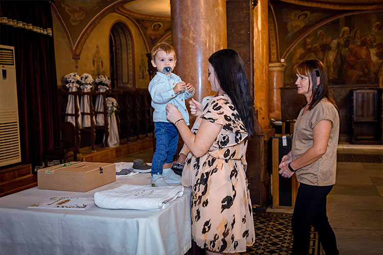 Кръстницата съблича момченцето преди кръщаването му в купела.