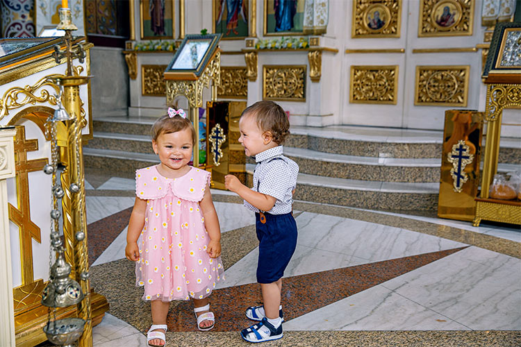 Момченце и момиченце се забавляват след края на ритуал Свето Кръщение в храм Свети Николай Мирликийски Чудотворец, град Пловдив.